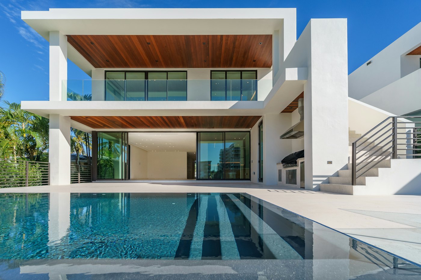 White cantilevered home with wood soffits over a pool