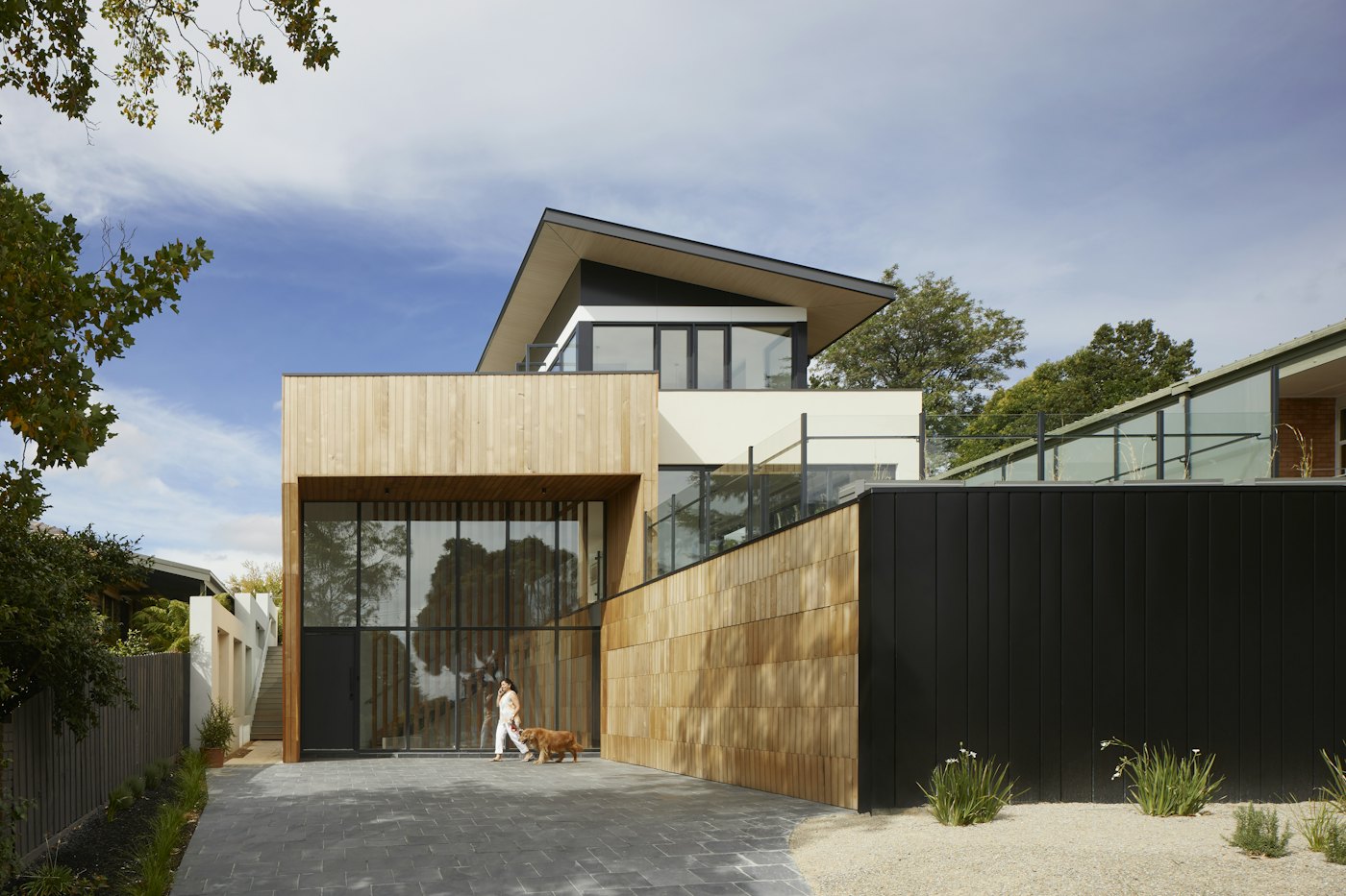Wood-clad modern home with a gravel drive